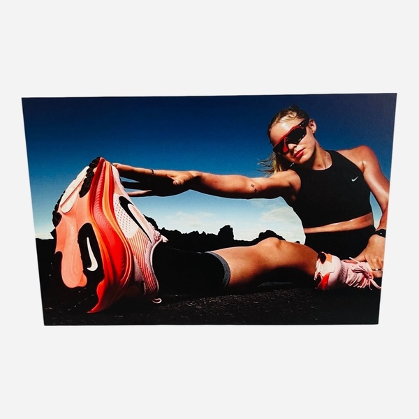 A low-angle, high-contrast shot of an athlete stretching while emphasizing a bold, brightly colored running shoe as the focal point.