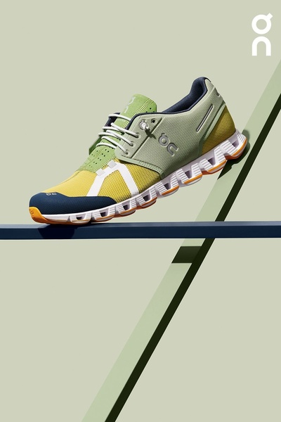 A high-contrast studio shot of a performance running shoe balanced on a structural ledge, emphasizing technical details and color blocking.