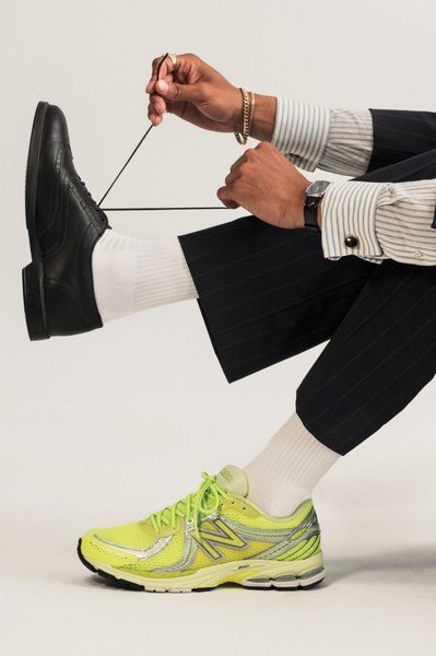 This creative displays a person wearing formal business attire with dress socks on one foot, while the other foot showcases a vibrant, neon-green technical running shoe.