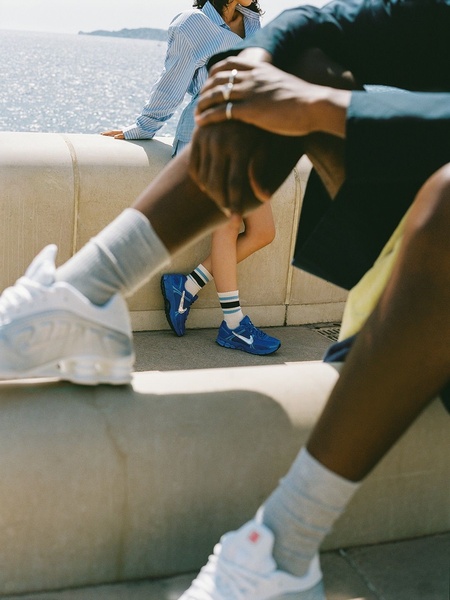A 3:4 portrait creative featuring a candid, lifestyle-oriented shot of a running shoe worn by a model in a relaxed outdoor environment.