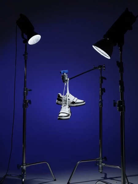 A clean, studio-lit shot of a running shoe hanging against a bold blue background, utilizing professional photography lighting to create a high-end feel.