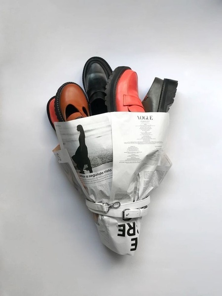 A creative product presentation featuring multiple loafer styles arranged like a flower bouquet wrapped in a newspaper.