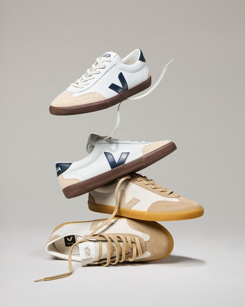 A vertical, gravity-defying stack of four sneakers against a neutral background, emphasizing the product's design and color palette.