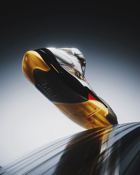 A striking, low-angle product shot of a running shoe resting on a curved, reflective surface, emphasizing its sleek design and premium build.