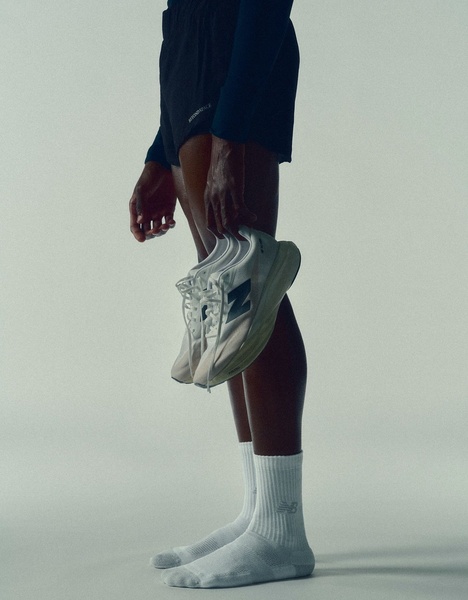 A close-up, monochromatic shot of a model holding a running shoe, emphasizing the clean lines and athletic aesthetic.
