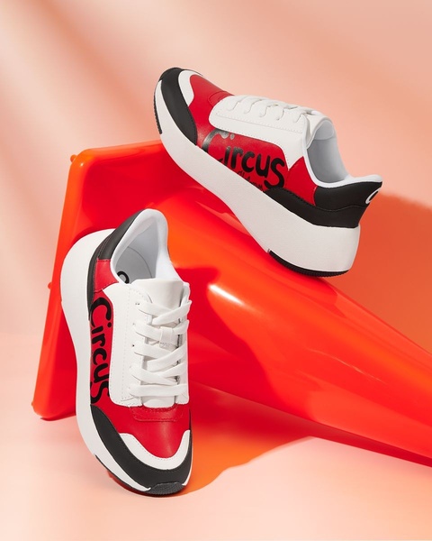 This ad creative utilizes a high-contrast, minimalist studio environment to highlight the design details and branding of a sneaker pair.
