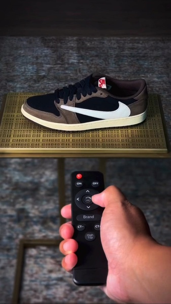 A creative featuring a single running shoe placed on a table while a hand holds a remote control, simulating an interactive product selector.