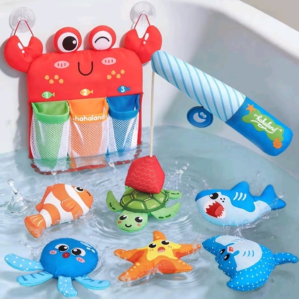 A high-angle product shot displaying a crab-shaped bath toy organizer mounted with suction cups, accompanied by various colorful sea-themed bath toys.
