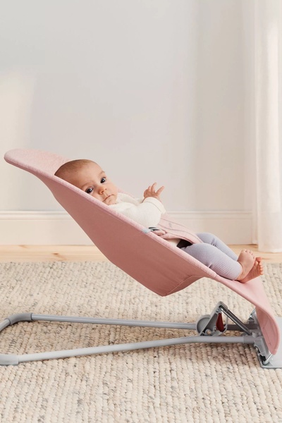 A high-quality product shot of a baby in a minimalist bouncer, utilizing soft pastels and natural lighting to emphasize comfort and safety.