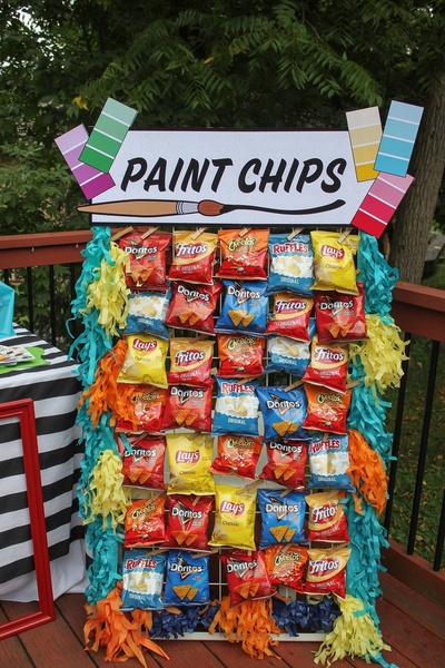 A creative visual display of various snack chip bags mounted on a wire rack with a clever 'Paint Chips' header, using color-coordinated organization.