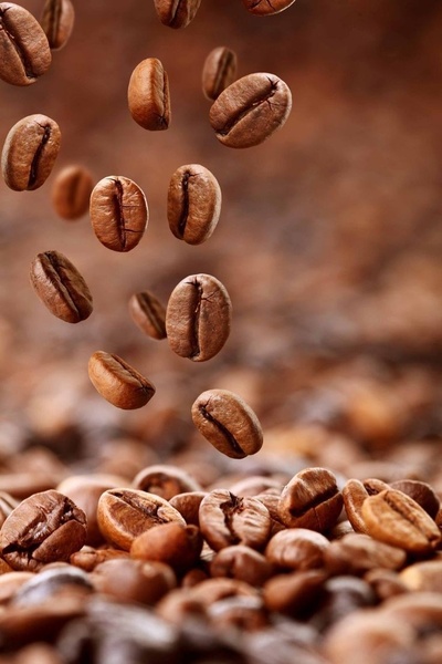 A high-resolution, vertical ad creative showcasing falling roasted coffee beans against a warm, deep brown background.