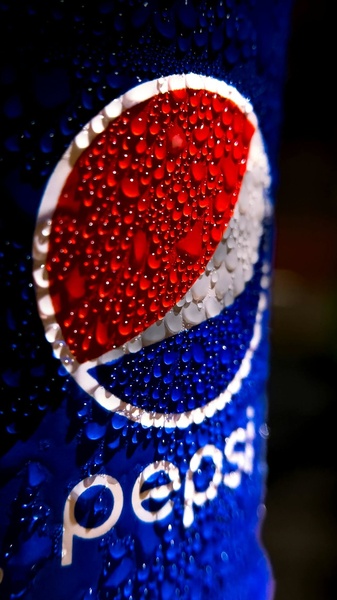 A high-definition macro shot of a soda can surface, emphasizing deep blue tones, intense red branding, and realistic condensation droplets.