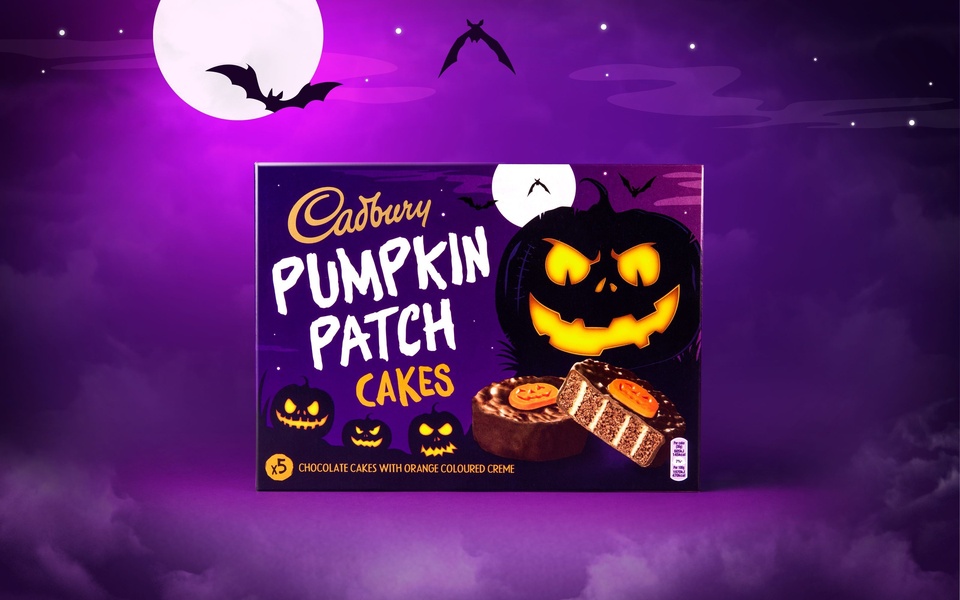 This seasonal chocolate cake ad features a dark, spooky Halloween theme with glowing pumpkin imagery and high-contrast colors.