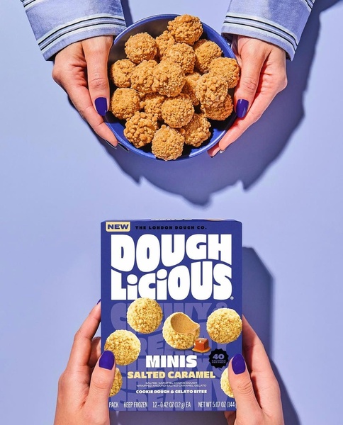 A top-down, symmetrical shot showing hands holding a bowl of cookie dough bites above the product packaging.