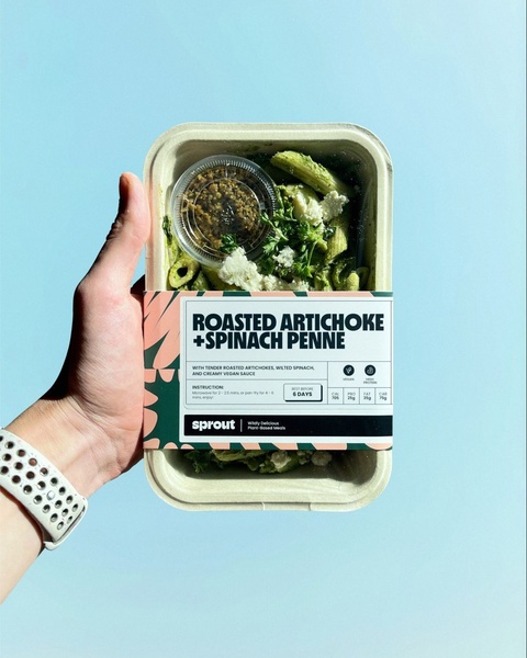 A high-clarity, top-down shot of a branded, single-serve pasta meal held in a hand against a solid, contrasting background.