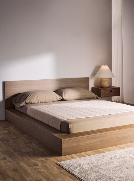 A high-quality studio shot of a low-profile platform bed featuring wood finishes, soft ambient lighting, and neutral decor.