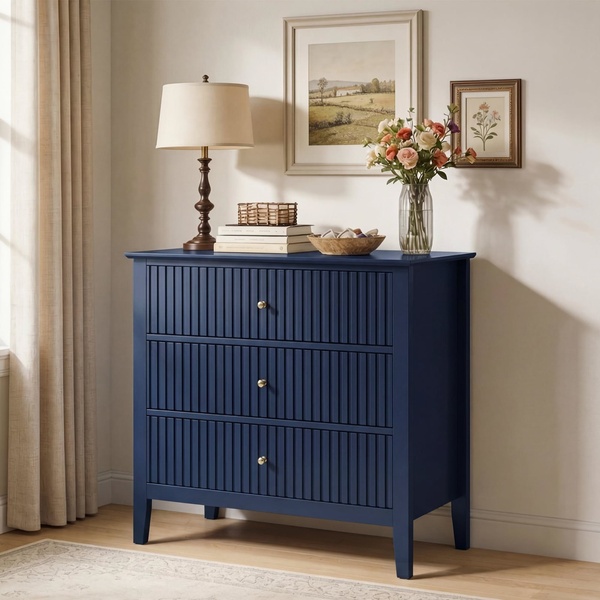 A high-resolution, static product image of a modern, blue three-drawer dresser styled in a warm, inviting home setting.
