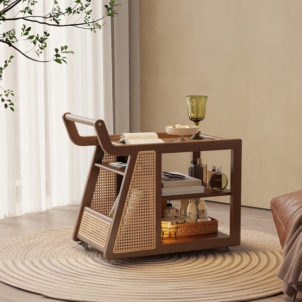 A high-quality lifestyle shot of a wooden rattan serving cart set in a sunlit, airy room, showcasing its utility and aesthetic design.
