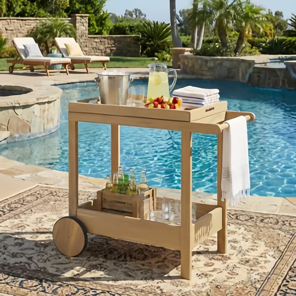A high-quality lifestyle shot of a wooden bar cart situated next to a swimming pool, conveying a relaxing summer atmosphere.