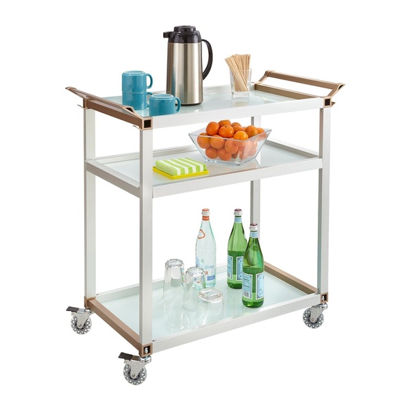 A high-key studio photograph of a modern glass and metal serving trolley, staged with breakfast essentials and beverages to highlight product utility.