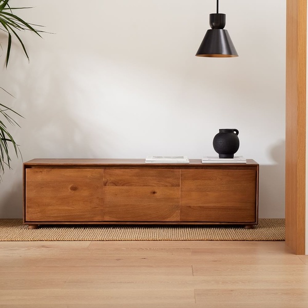 A high-quality product hero shot featuring a wooden media console in a neutral, modern living space.
