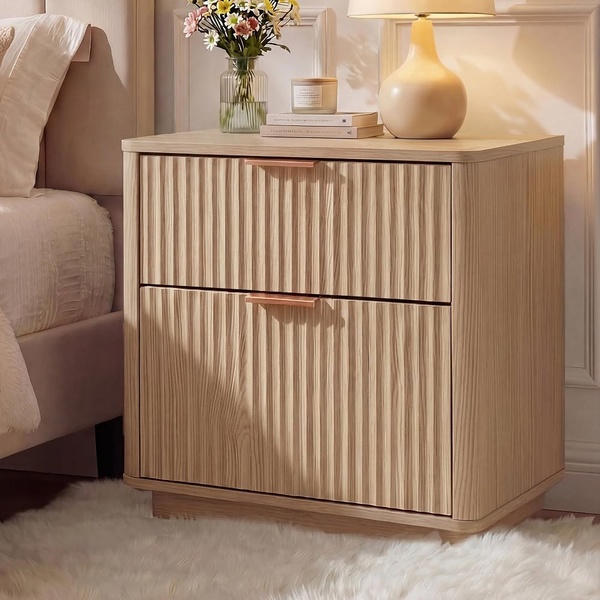 A clean, high-resolution lifestyle shot of a fluted wooden nightstand styled with a lamp and flowers in a bedroom setting.