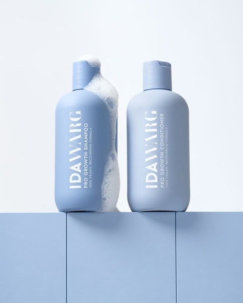 A clean, high-contrast studio shot of shampoo and conditioner bottles featuring an active foam texture to signal product efficacy.