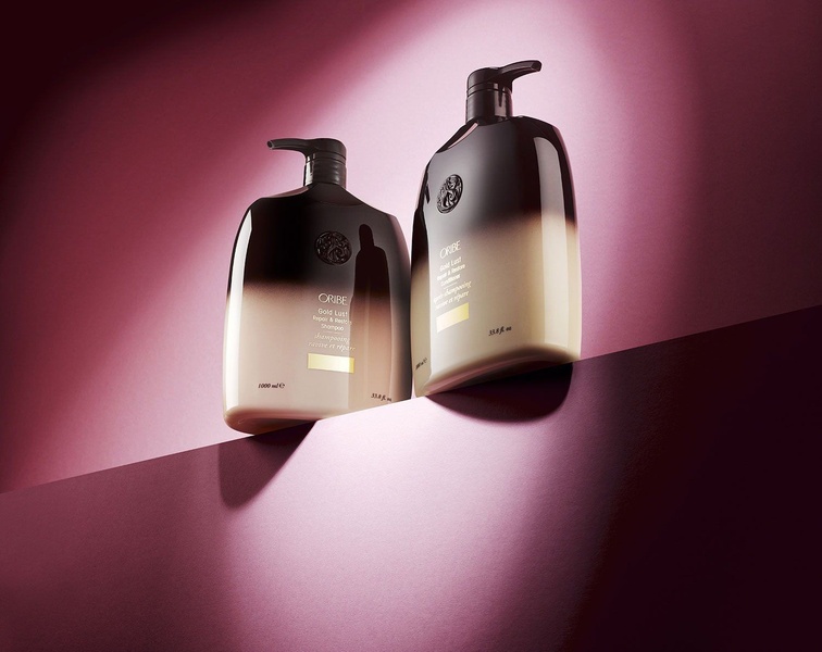 A clean, high-contrast product hero shot featuring premium shampoo and conditioner bottles against a deep magenta curved studio background.