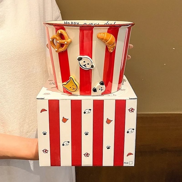A clean, studio-lit photograph showcasing a striped ceramic bucket featuring 3D snack-themed icons and playful animal graphics.