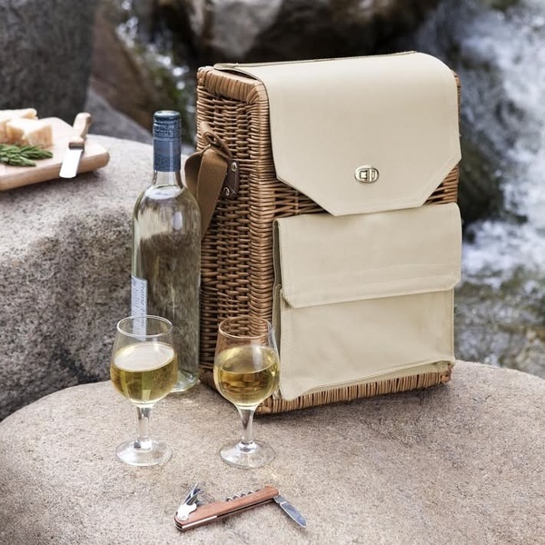 A high-quality image showcasing a premium picnic basket alongside wine and glasses in a natural, scenic outdoor location.