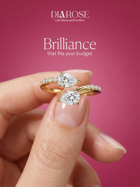 A close-up, high-resolution shot of a hand holding a pear-cut lab diamond ring against a vibrant magenta background.