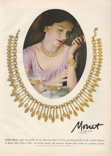 A classic, oval-framed editorial photograph featuring a woman wearing an elaborate gold necklace and matching bracelet while dining.