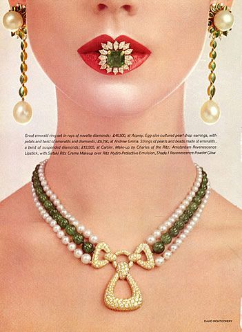 A striking close-up shot featuring a model wearing a luxurious pearl and emerald necklace, with a large emerald ring placed between her lips.