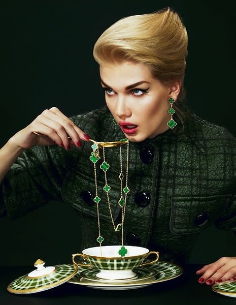 A high-fashion, surrealist studio shot featuring a model elegantly using a spoon to serve jewelry as if it were tea.