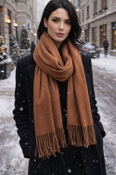 A high-quality lifestyle image of a model wearing a premium brown scarf in a snowy, urban setting.