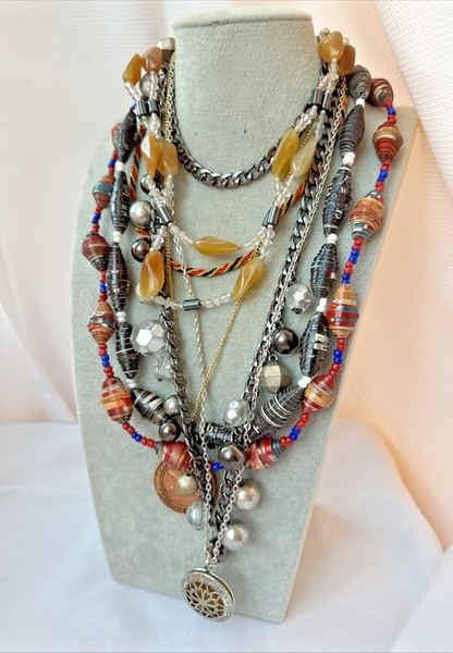 A close-up studio shot of a layered bohemian-style necklace set displayed on a grey mannequin bust.