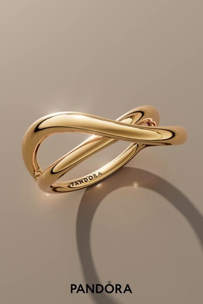 A high-end, clean product shot of a gold ring against a neutral background, emphasizing material texture and light.