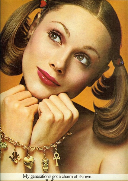 A close-up, high-fashion portrait shot of a model wearing a gold charm bracelet with nostalgic icons, set against a warm, monochromatic orange backdrop.