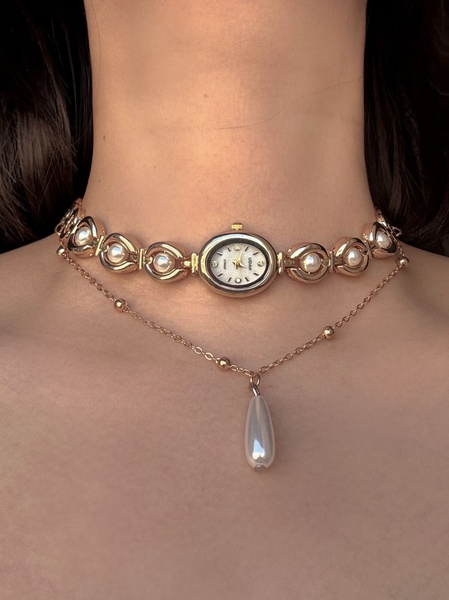 A close-up, high-detail shot of a pearl and gold-tone choker featuring an integrated watch face, creating a sophisticated luxury look.