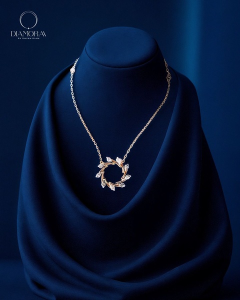 A high-end studio shot of a gold necklace with a floral-inspired design draped over a deep blue velvet display on a rich blue background.
