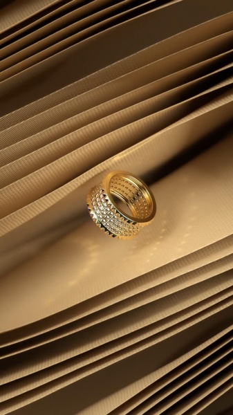 A high-end jewelry advertisement featuring a single gold diamond-encrusted band floating against pleated gold-toned paper textures.