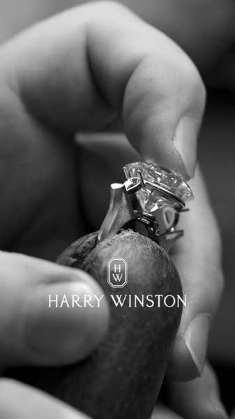 A close-up, black and white shot of a jeweler holding a diamond ring to emphasize precision, quality, and the human touch in luxury production.