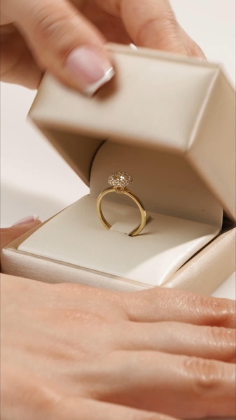 A close-up, high-angle shot focusing on the opening of a premium jewelry box to reveal a sparkling engagement ring. The aesthetic emphasizes clean lines and soft lighting.