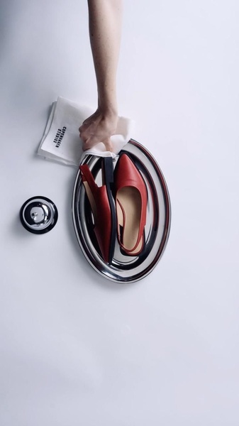 A high-angle studio shot of red leather slingback flats served on a silver platter, mimicking a hotel room service experience.
