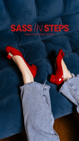 A close-up, top-down perspective of high-gloss red patent leather pumps worn with casual light-wash denim, set against a deep blue velvet texture.