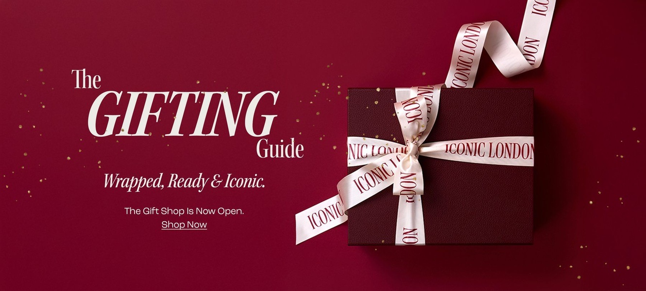 A high-end 21:9 landscape creative featuring a luxury gift box wrapped with branded ribbon on a deep burgundy backdrop, utilizing a minimalist, aspirational aesthetic.