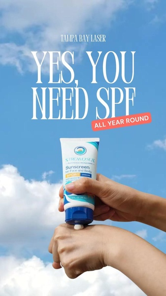 A close-up shot of a hand applying sunscreen against a clear blue sky, emphasizing the necessity of daily sun protection.