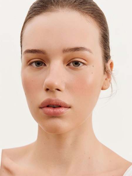 A high-quality, close-up portrait of a model showcasing natural skin texture and a clean, neutral background.