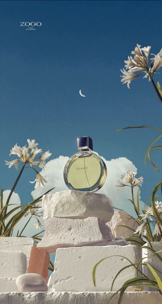 A high-end perfume bottle resting on white stone blocks against a blue sky, accented by white flowers and a crescent moon.