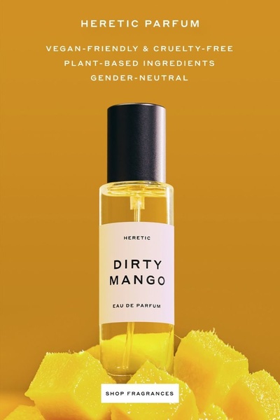 A high-end, clean product shot of a perfume bottle centered on a bright yellow background surrounded by mango slices.
